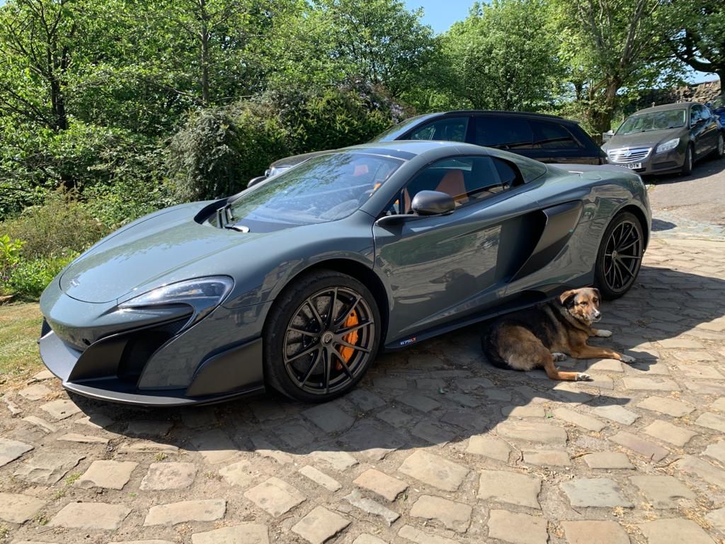 Grey McLaren convertible parked on a stone drive