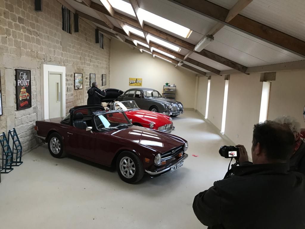 Burgundy Triumph TR6 with a group of classic cars