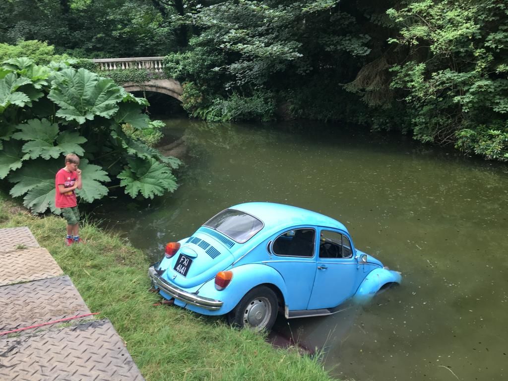 Blue classic Volkswagen Beetle partly in shallow water