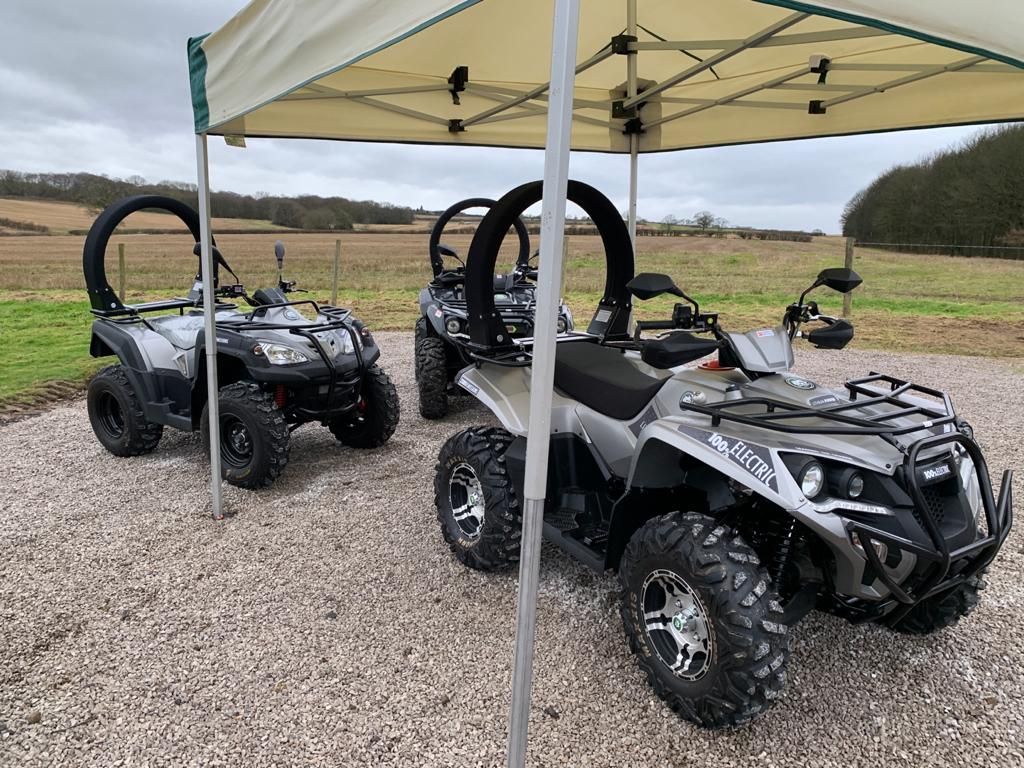 Three grey and black utility quad bikes under a canopy